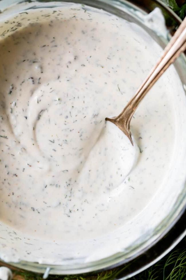 Κρεμώδης Σως Ranch με Βουτυρόγαλα από το The Food Charlatan. Το μόνο πράγμα που είναι καλύτερο από την έτοιμη σως ranch εστιατορίου είναι η Σπιτική Σως Ranch με Βουτυρόγαλα! Είναι τόσο ονειρεμένη, κρεμώδης και η συνταγή είναι απίστευτα εύκολη. Θα σας δείξω πώς ακριβώς να την φτιάξετε! Ετοιμαστείτε για την καλύτερη σαλάτα της ζωής σας! #ranch #dip #easy #recipe #salad #healthy #buttermilk #sourcream #freshherbs #dried #spices #homemade #fromscratch #restaurant #diy #howtomake Φωτογραφία από ψηλά κρεμώδους σως ranch με βουτυρόγαλα σε ένα γυάλινο μπολ με ένα κουτάλι μέσα.