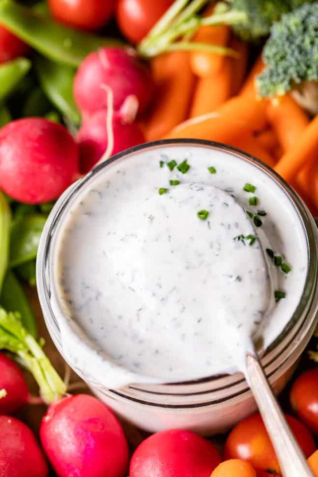 Κρεμώδης Σως Ranch με Βουτυρόγαλα από το The Food Charlatan. Το μόνο πράγμα που είναι καλύτερο από την έτοιμη σως ranch εστιατορίου είναι η Σπιτική Σως Ranch με Βουτυρόγαλα! Είναι τόσο ονειρεμένη, κρεμώδης και η συνταγή είναι απίστευτα εύκολη. Θα σας δείξω πώς ακριβώς να την φτιάξετε! Ετοιμαστείτε για την καλύτερη σαλάτα της ζωή σας! #ranch #dip #easy #recipe #salad #healthy #buttermilk #sourcream #freshherbs #dried #spices #homemade #fromscratch #restaurant #diy #howtomake Σως ranch με βουτυρόγαλα σε γυάλινο βάζο περιτριγυρισμένο από φρέσκα λαχανικά.