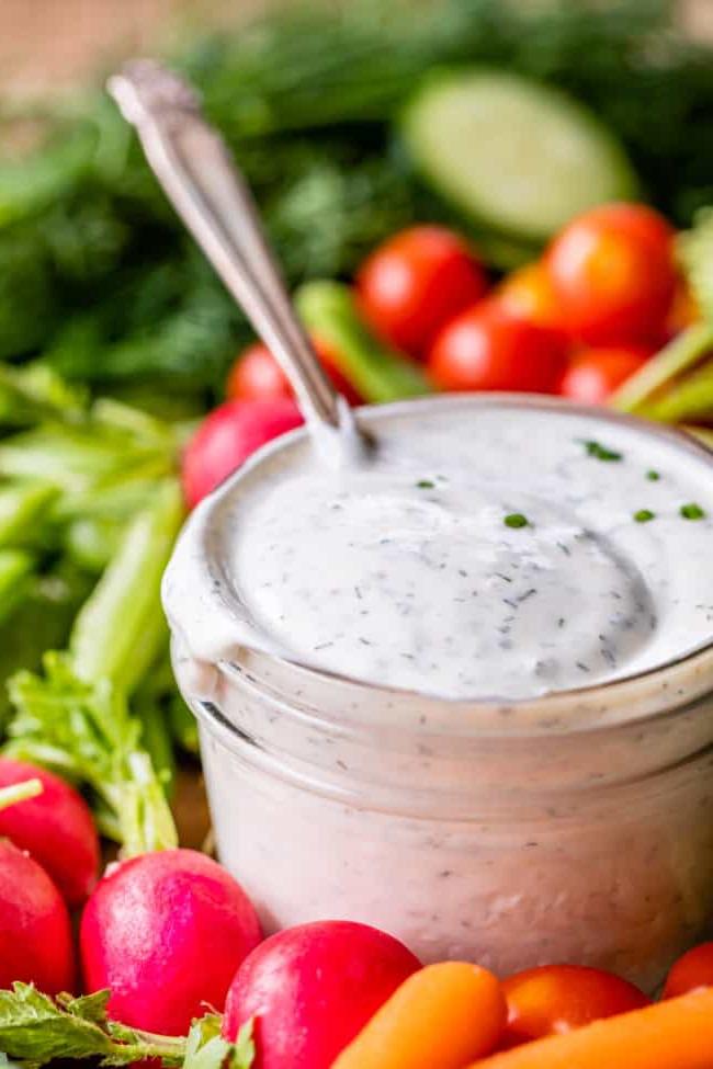 Κρεμώδης Σως Ranch με Βουτυρόγαλα από το The Food Charlatan. Το μόνο πράγμα που είναι καλύτερο από την έτοιμη σως ranch εστιατορίου είναι η Σπιτική Σως Ranch με Βουτυρόγαλα! Είναι τόσο ονειρεμένη, κρεμώδης και η συνταγή είναι απίστευτα εύκολη. Θα σας δείξω πώς ακριβώς να την φτιάξετε! Ετοιμαστείτε για την καλύτερη σαλάτα της ζωής σας! #ranch #dip #easy #recipe #salad #healthy #buttermilk #sourcream #freshherbs #dried #spices #homemade #fromscratch #restaurant #diy #howtomake Σως ranch με βουτυρόγαλα σε ένα γυάλινο βάζο με ένα κουτάλι, περιτριγυρισμένο από φρέσκα λαχανικά.