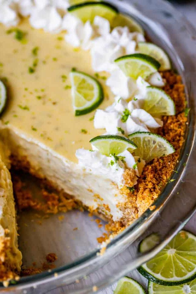 Ένα πάι Key Lime με σαντιγί και φέτες λάιμ, με ένα κομμάτι κομμένο.