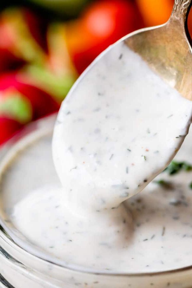 Κρεμώδης Σως Ranch με Βουτυρόγαλα από το The Food Charlatan. Το μόνο πράγμα που είναι καλύτερο από την έτοιμη σως ranch εστιατορίου είναι η Σπιτική Σως Ranch με Βουτυρόγαλα! Είναι τόσο ονειρεμένη, κρεμώδης και η συνταγή είναι απίστευτα εύκολη. Θα σας δείξω πώς ακριβώς να την φτιάξετε! Ετοιμαστείτε για την καλύτερη σαλάτα της ζωής σας! #ranch #dip #easy #recipe #salad #healthy #buttermilk #sourcream #freshherbs #dried #spices #homemade #fromscratch #restaurant #diy #howtomake Ένα κουτάλι βυθίζεται σε ένα βάζο με σπιτική σως ranch με βουτυρόγαλα.