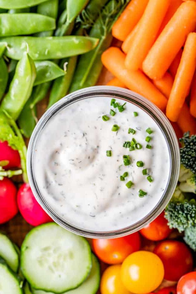 Κρεμώδης Σως Ranch με Βουτυρόγαλα από το The Food Charlatan. Το μόνο πράγμα που είναι καλύτερο από την έτοιμη σως ranch εστιατορίου είναι η Σπιτική Σως Ranch με Βουτυρόγαλα! Είναι τόσο ονειρεμένη, κρεμώδης και η συνταγή είναι απίστευτα εύκολη. Θα σας δείξω πώς ακριβώς να την φτιάξετε! Ετοιμαστείτε για την καλύτερη σαλάτα της ζωής σας! #ranch #dip #easy #recipe #salad #healthy #buttermilk #sourcream #freshherbs #dried #spices #homemade #fromscratch #restaurant #diy #howtomake Φωτογραφία από ψηλά σως ranch με βουτυρόγαλα σε ένα γυάλινο βάζο με φρέσκα λαχανικά να το περιβάλλουν.