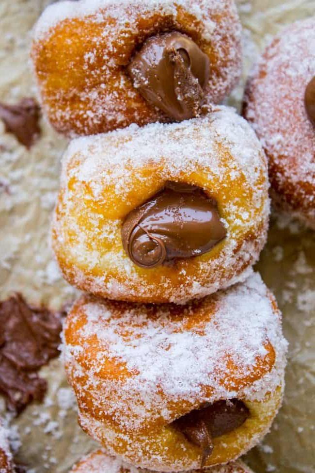 Συνταγή για Ντόνατς Γεμιστά με Nutella από το The Food Charlatan. Αυτή η συνταγή Nutella ντόνατς φτιάχνει τα πιο αφράτα ντόνατς με μαγιά. Γεμάτα με ζεστή Nutella! Πολλές φωτογραφίες δείχνουν ακριβώς πώς να φτιάξετε ντόνατς. #ντόνατς #σπιτικά #απότομη_αρχή #Nutella #γεμιστά_Nutella #γεμιστά_ντόνατς #τηγανητά #σοκολάτα #μαγιά #ζάχαρη Μια στοίβα από ντόνατς που δείχνει τη γέμιση Nutella