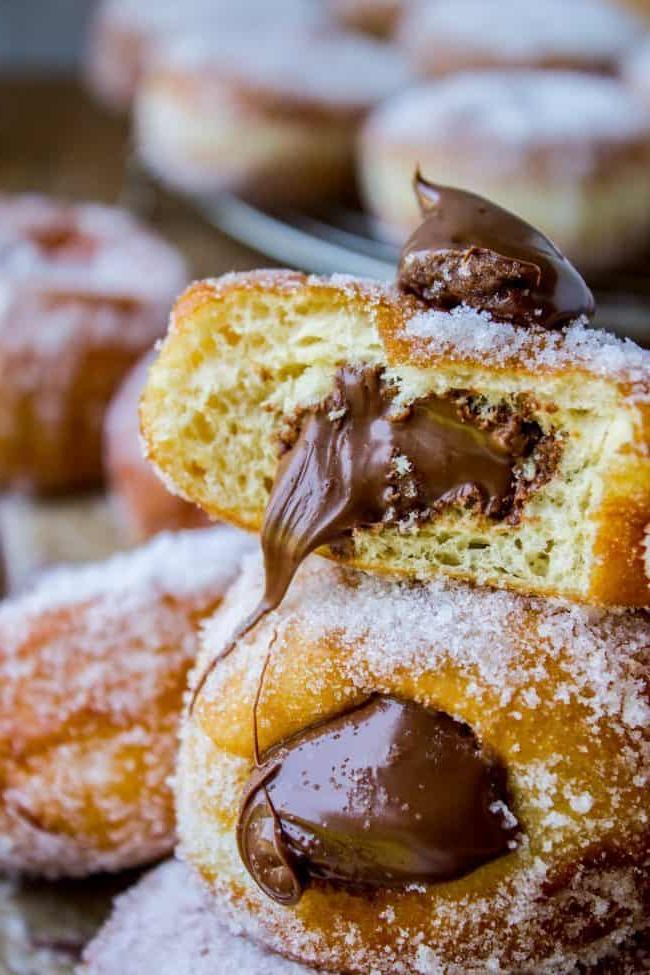 Συνταγή για Ντόνατς Γεμιστά με Nutella από το The Food Charlatan. Αυτή η συνταγή Nutella ντόνατς φτιάχνει τα πιο αφράτα ντόνατς με μαγιά. Γεμάτα με ζεστή Nutella! Πολλές φωτογραφίες δείχνουν ακριβώς πώς να φτιάξετε ντόνατς. #ντόνατς #σπιτικά #απότομη_αρχή #Nutella #γεμιστά_Nutella #γεμιστά_ντόνατς #τηγανητά #σοκολάτα #μαγιά #ζάχαρη Ένα γεμιστό ντόνατς με ένα κομμάτι φαγωμένο