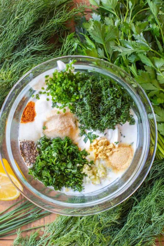 Κρεμώδης Σως Ranch με Βουτυρόγαλα από το The Food Charlatan. Το μόνο πράγμα που είναι καλύτερο από την έτοιμη σως ranch εστιατορίου είναι η Σπιτική Σως Ranch με Βουτυρόγαλα! Είναι τόσο ονειρεμένη, κρεμώδης και η συνταγή είναι απίστευτα εύκολη. Θα σας δείξω πώς ακριβώς να την φτιάξετε! Ετοιμαστείτε για την καλύτερη σαλάτα της ζωής σας! #ranch #dip #easy #recipe #salad #healthy #buttermilk #sourcream #freshherbs #dried #spices #homemade #fromscratch #restaurant #diy #howtomake Φρέσκα μυρωδικά και μπαχαρικά προστίθενται σε ντρέσινγκ σε γυάλινο βάζο, περιτριγυρισμένο από φρέσκα μυρωδικά και λεμόνια.