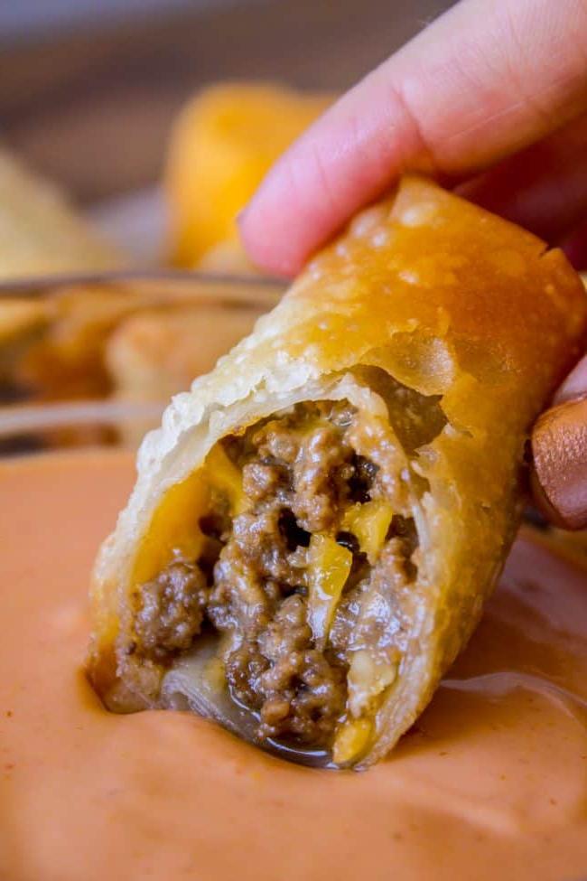 Τυρομπέργκερ Ρολά Αυγού από το The Food Charlatan. Πρόκειται για έναν από τους καλύτερους συνδυασμούς όλων των εποχών! Εννοώ, γέμιση κιμά με τυρί τηγανισμένη σε φύλλα; Πώς μπορεί να πάει κάτι στραβά εδώ; Βουτήξτε τα σε μια υπέροχη σάλτσα τηγανίσματος και θα βρεθείτε στον παράδεισο του τυρομπέργκερ σε χρόνο μηδέν! #τυρομπέργκερ #μπέργκερ #κιμάς #τυρί #τηγανητό #βαθύτηγανισμένο #εύκολο #συνταγή #μοσχάρι #σπιτικό #πώς_να_φτιάξεις #σάλτσα_τηγανίσματος #ορεκτικό #ντιπ Βουτώντας ένα τυρομπέργκερ ρολό αυγού σε σάλτσα τηγανίσματος.