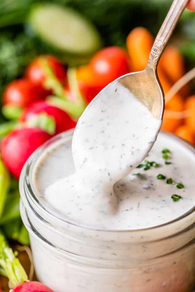 Κρεμώδης Σως Ranch με Βουτυρόγαλα από το The Food Charlatan. Το μόνο πράγμα που είναι καλύτερο από την έτοιμη σως ranch εστιατορίου είναι η Σπιτική Σως Ranch με Βουτυρόγαλα! Είναι τόσο ονειρεμένη, κρεμώδης και η συνταγή είναι απίστευτα εύκολη. Θα σας δείξω πώς ακριβώς να την φτιάξετε! Ετοιμαστείτε για την καλύτερη σαλάτα της ζωή σας! #ranch #dip #easy #recipe #salad #healthy #buttermilk #sourcream #freshherbs #dried #spices #homemade #fromscratch #restaurant #diy #howtomake Κρεμώδης σως ranch με βουτυρόγαλα με κουτάλι να βυθίζεται σε γυάλινο βάζο με φρέσκα λαχανικά στο παρασκήνιο.