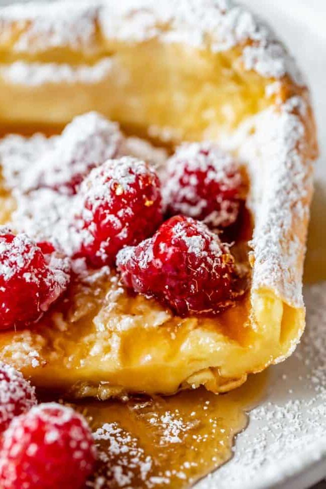 Dutch Baby με σμέουρα, σιρόπι και ζάχαρη άχνη.
