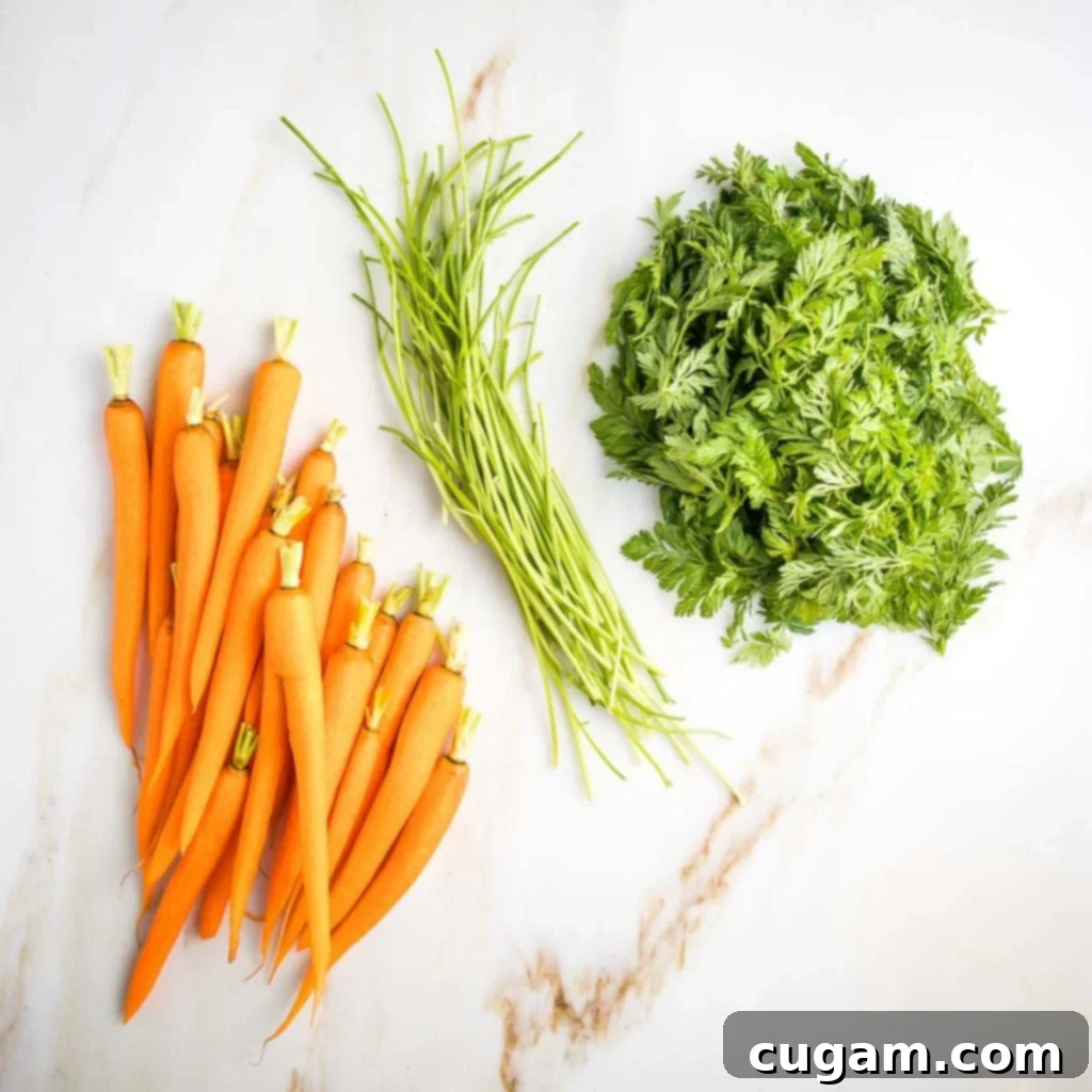Trimmed carrots, separated from their thick green stems and leafy carrot tops on a cutting board.