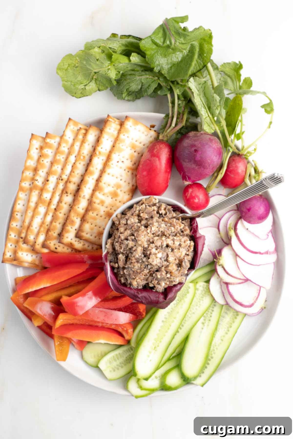 Nourishing Passover 2025: 60+ Wholesome Recipes for a Delicious Celebration 3 Vegetarian Chopped Liver in a small dish surrounded by raw vegetables and matzo crackers.