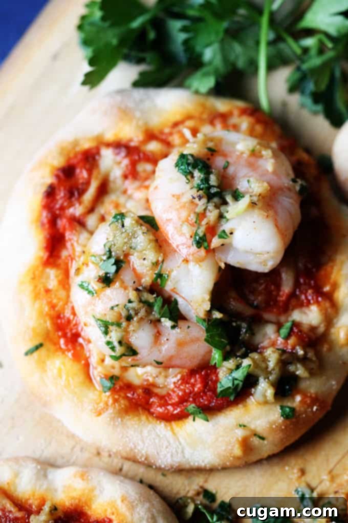 Pizzette with Garlic Shrimp and Roasted Pepper Pesto on a pizza peel, ready to be served.