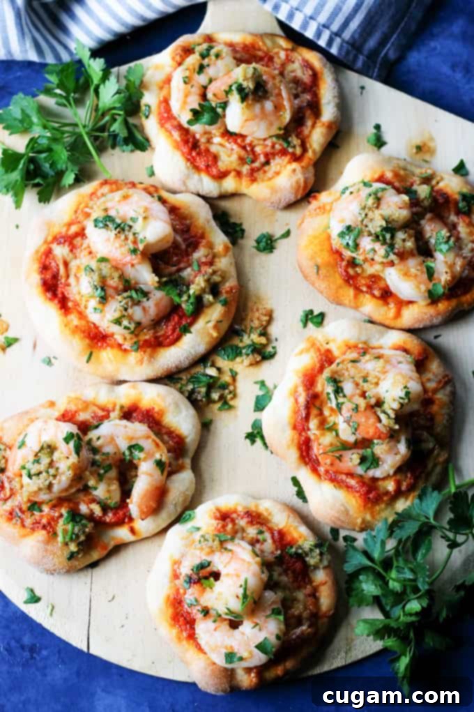 Pizzette with Garlic Shrimp and Roasted Red Pepper Pesto on a wooden pizza peel with a rustic blue background.