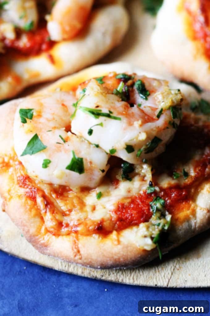 Close-up of a delicious pizzette topped with garlic shrimp, fresh parsley, and vibrant red pepper pesto.