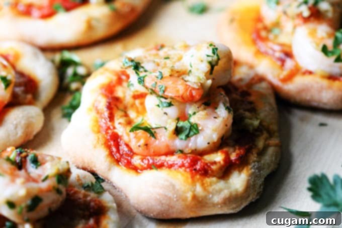 Close up of a finished pizzette with garlic shrimp and roasted red pepper pesto, garnished with fresh parsley.