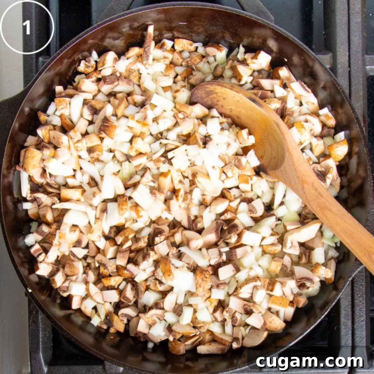 Diced onions and mushrooms in a cast iron skillet with a wooden spoon.