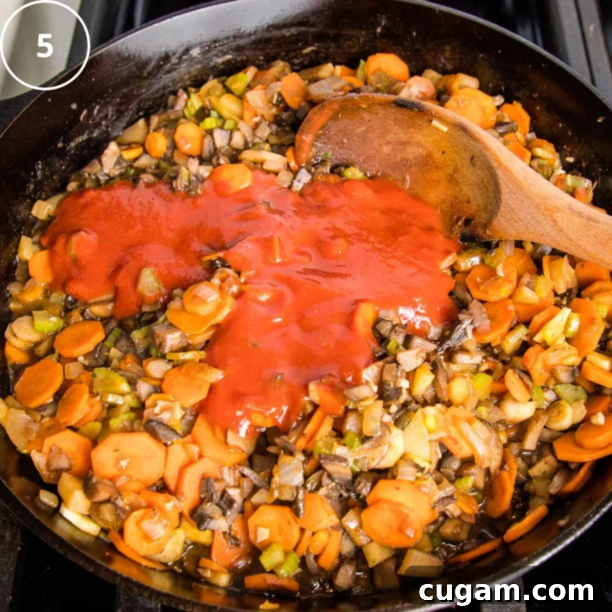 Sauteed veggies in a cast iron skillet with tomato sauce poured over the top.