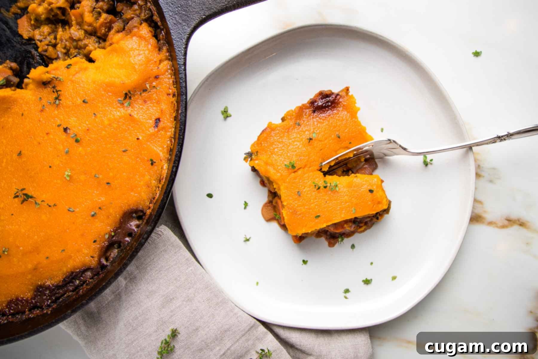Skillet shepherd's pie on left with a white plate holding a piece of shepherd's pie topped with sweet potato mash, sprinkled with fresh thyme.