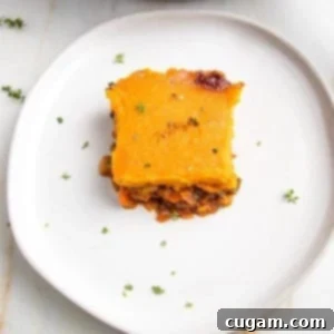 White rimmed plate with a square of veggie shepherd's pie, topped with sweet potato mash, sprinkled with fresh thyme.
