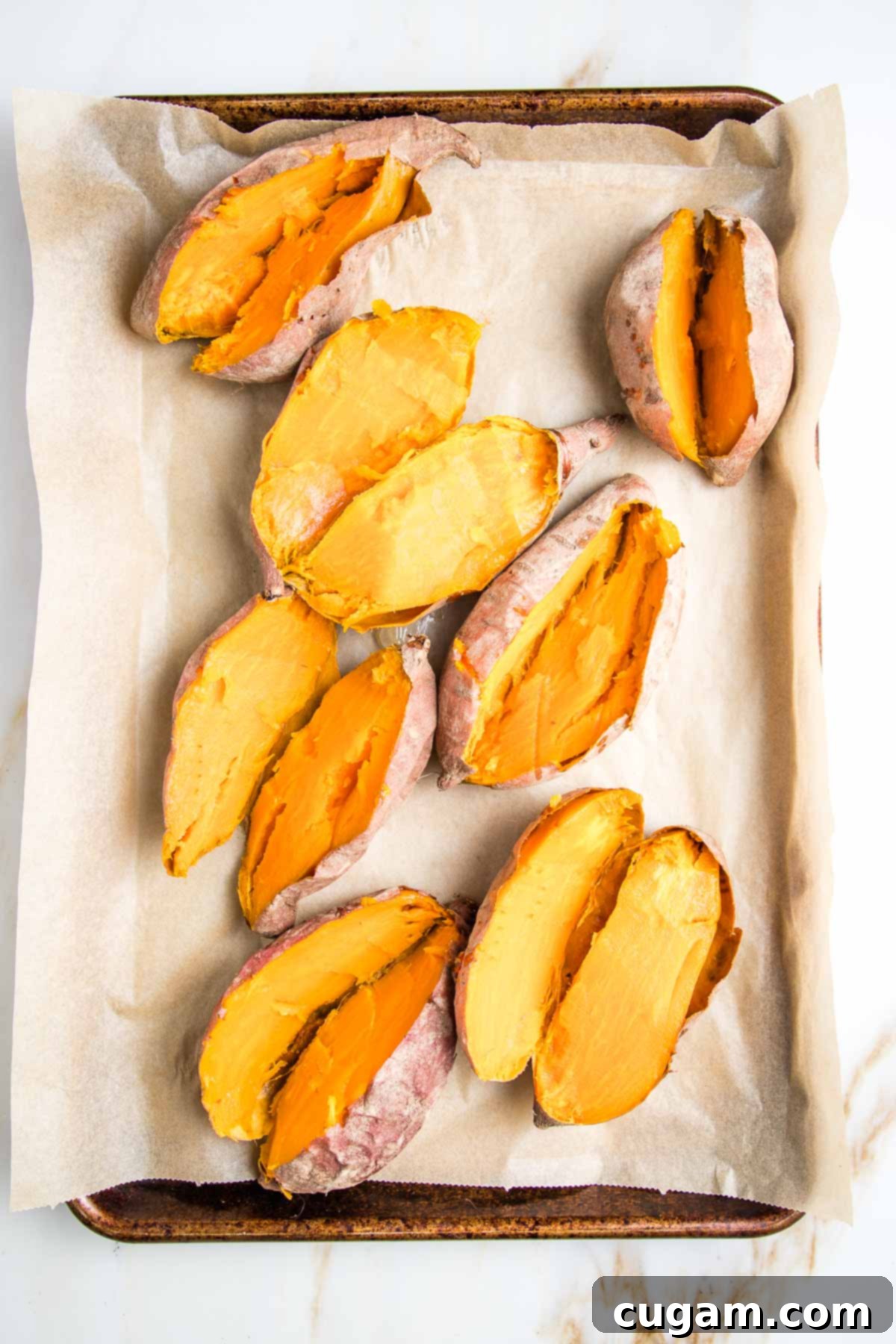 Baked sweet potatoes that have been cut in half to expose their orange flesh. 