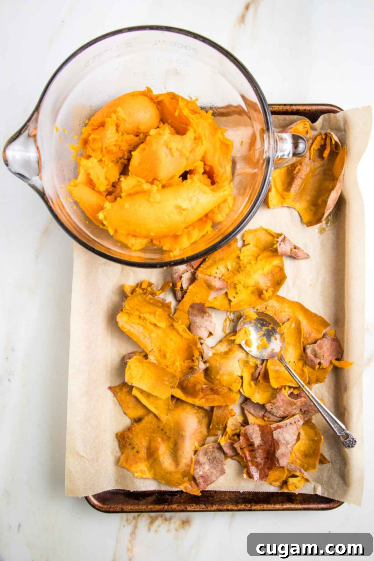 Scooping out the bright orange flesh from the skins of baked sweet potatoes.