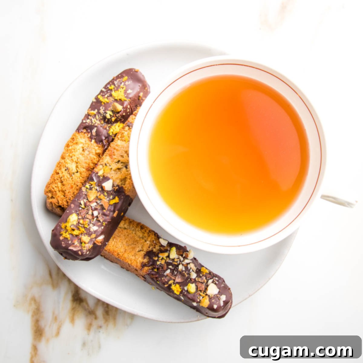 Large cup of tea with three chocolate dipped biscotti on the side. 