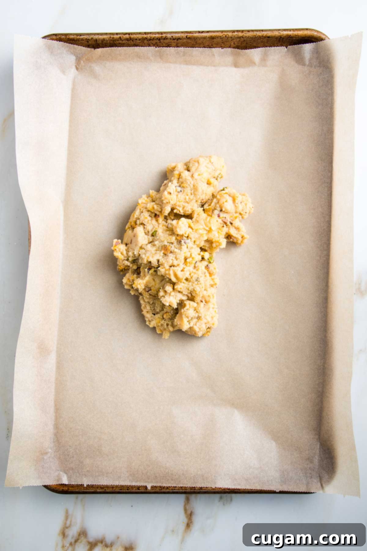 Dough in a heap on a baking sheet lined with parchment paper.
