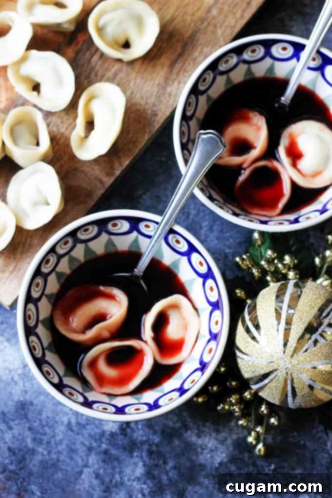 Two vibrant blue bowls filled with traditional Polish Borscht, each containing delicate mushroom Uszka.