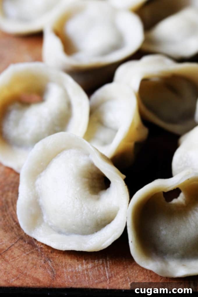 A large pile of freshly made mushroom pierogi Uszka, ready to be cooked or served, showcasing their intricate shape.