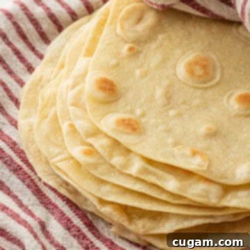 Stack of cooked tortillas in dish towel.