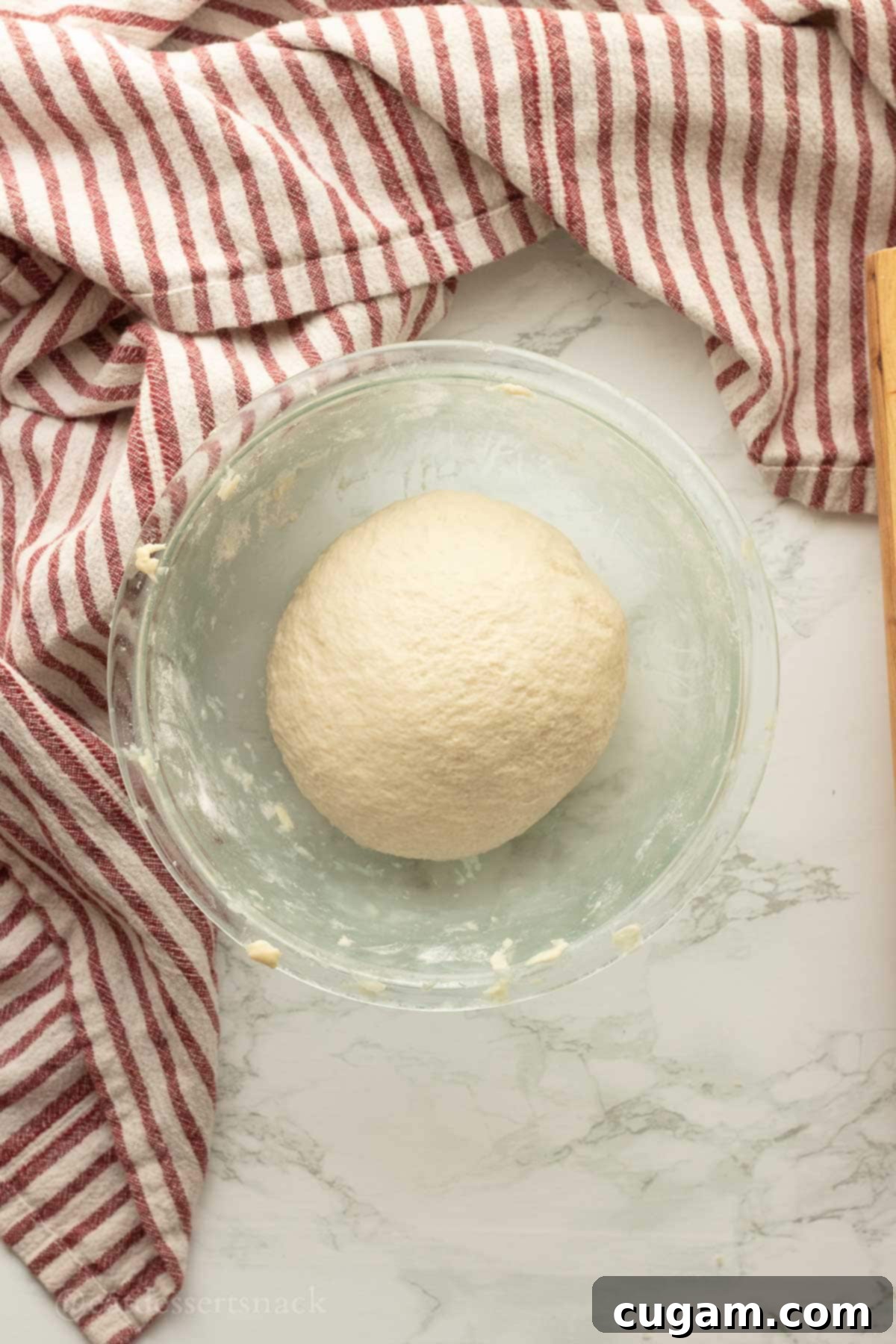 A smooth, elastic ball of sourdough discard tortilla dough resting in a glass bowl.