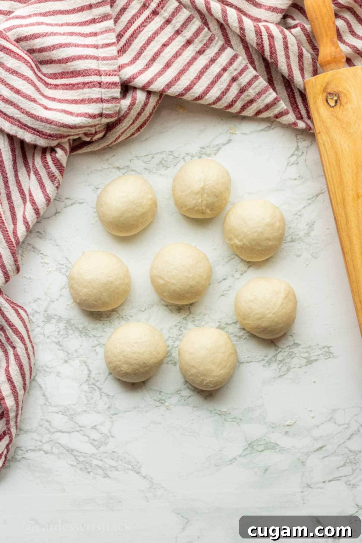 Eight perfectly rolled balls of sourdough discard tortilla dough resting on a countertop, covered and ready for their resting period.