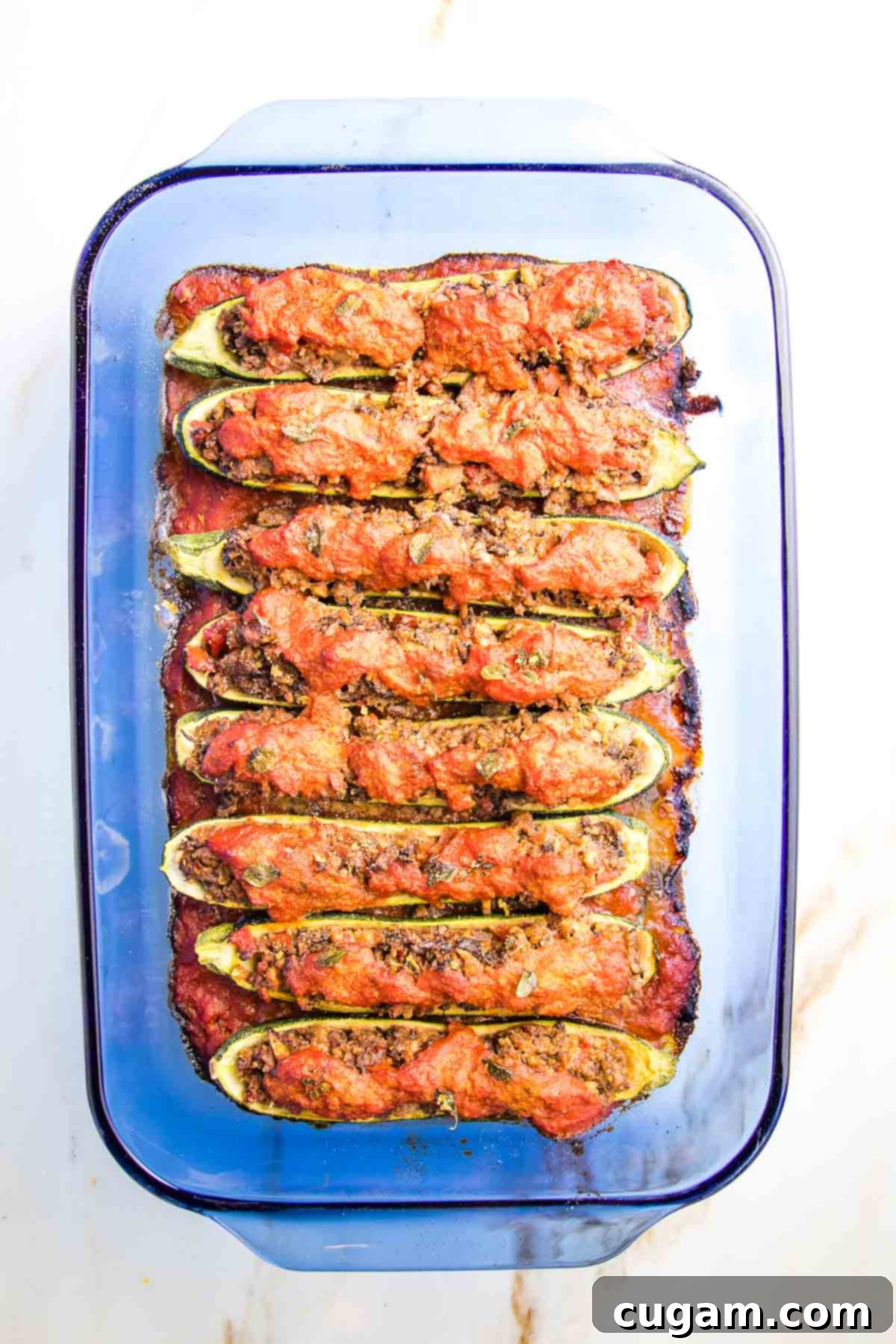 Perfectly baked stuffed zucchini boats, hot and bubbling, nestled in a casserole dish, ready to be served. The tops are crisp, and the filling looks tender and rich.