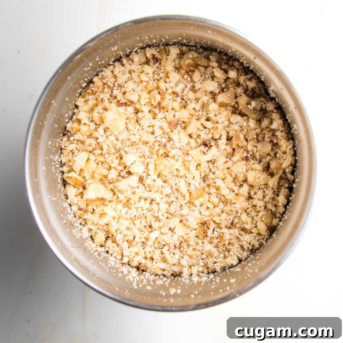 Finely ground walnuts in the bowl of a spice grinder, showcasing a textured consistency rather than a powdery one.
