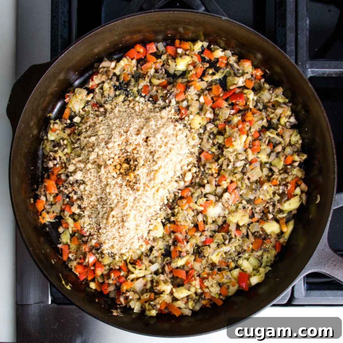 The skillet mixture with sautéed vegetables now includes finely chopped walnuts and a drizzle of tamari, ready to be fully incorporated into the savory filling.
