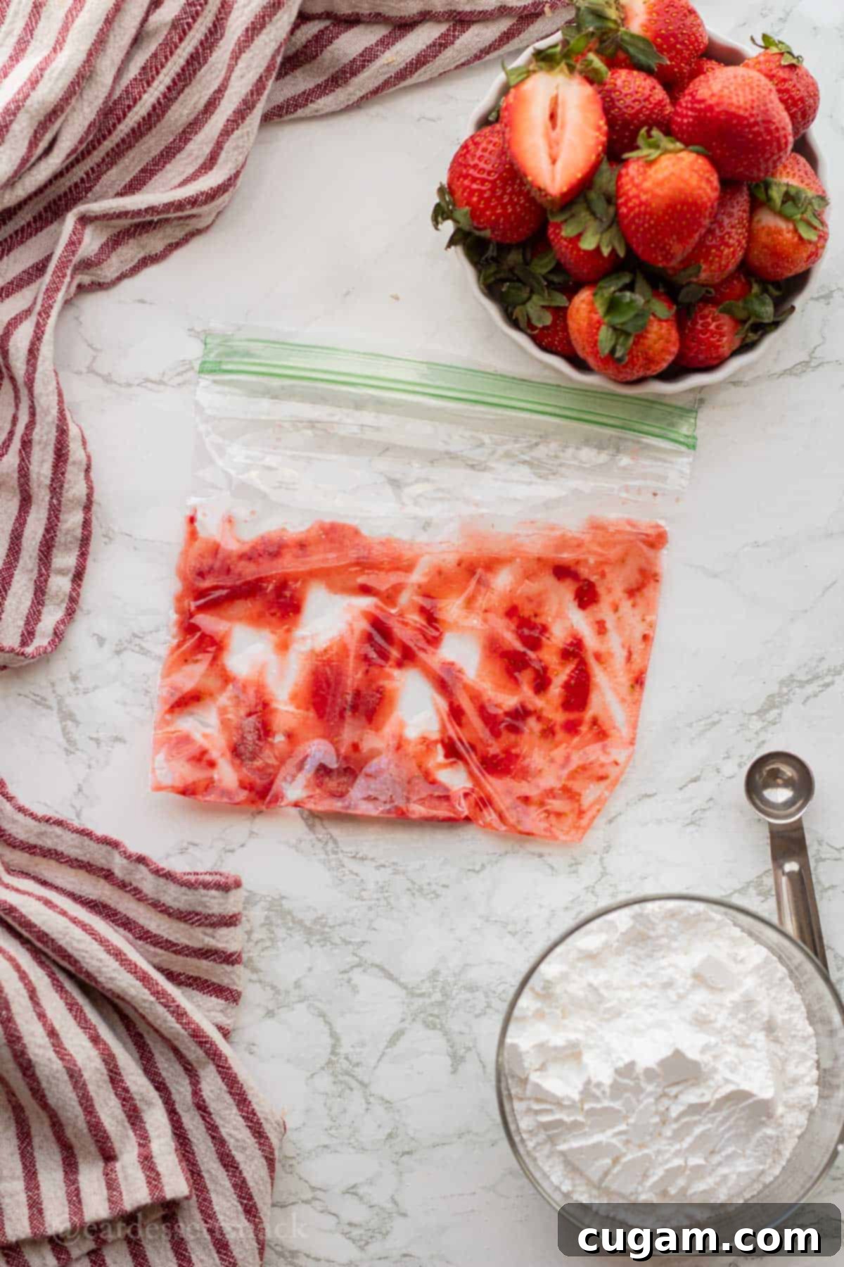 Mashed fresh strawberries in a plastic resealable bag on a marble countertop, ready for making the glaze.