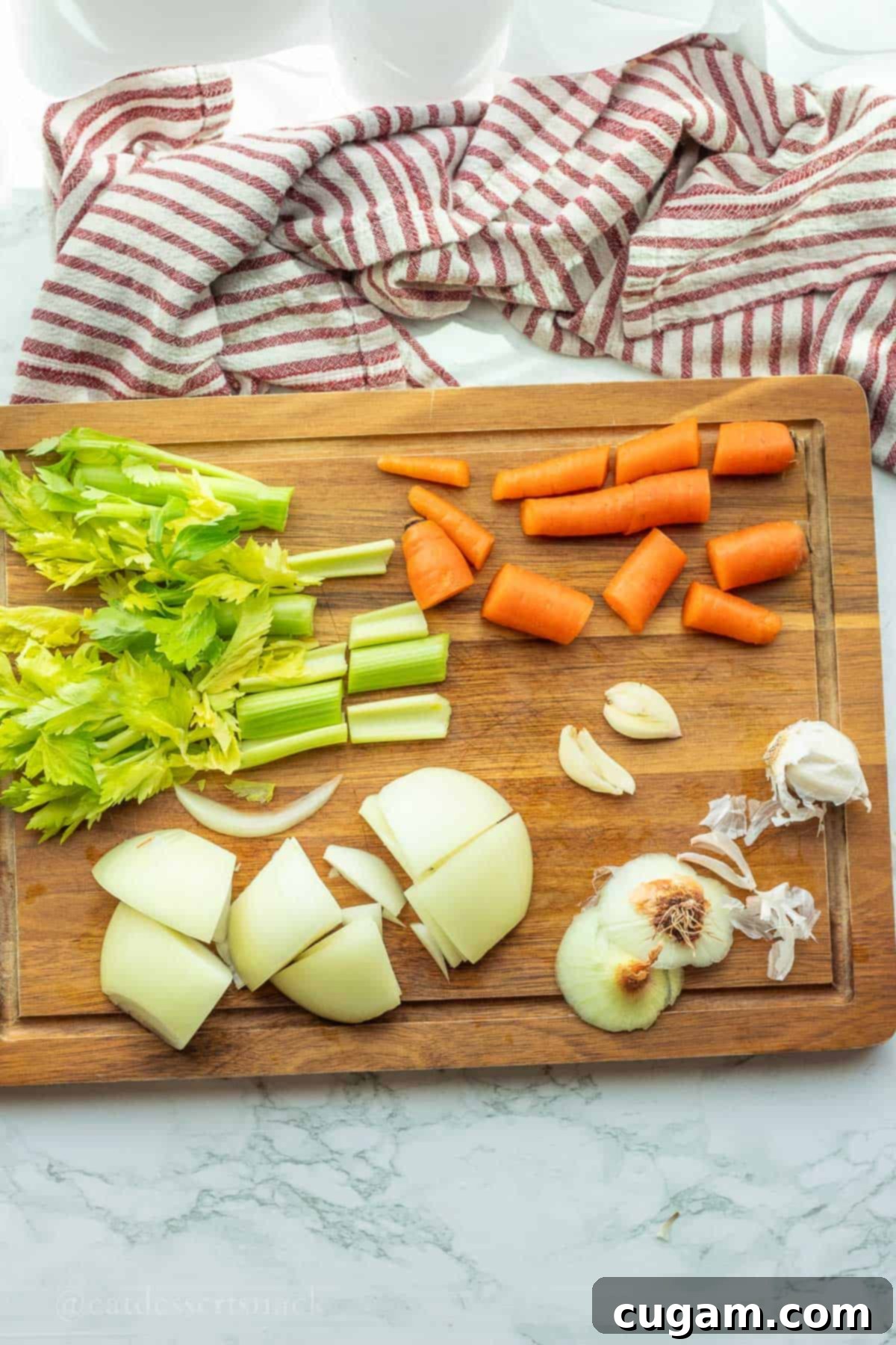 Chopped vegetables (carrots, celery, onion) on a wood cutting board, prepped for bone broth.