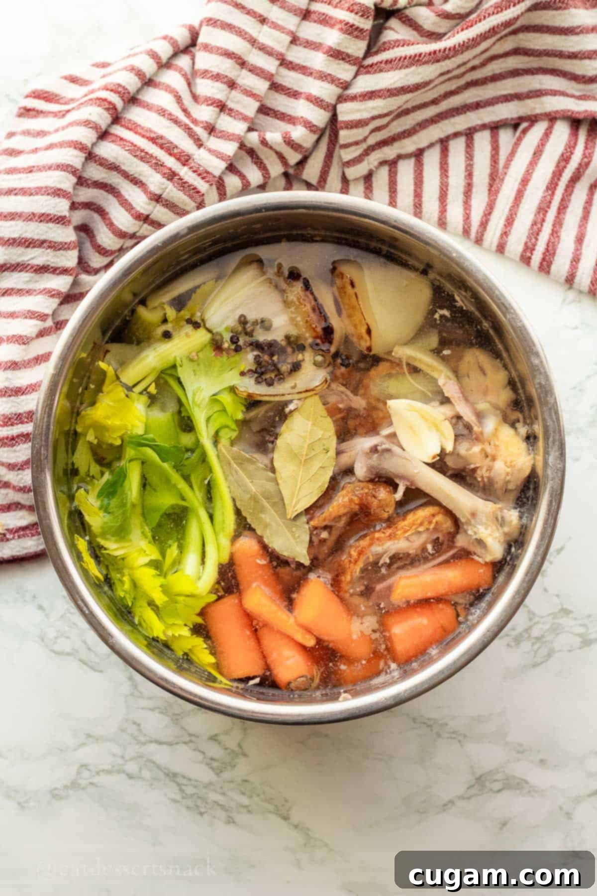 Raw chicken bones and chopped vegetables submerged in water inside an Instant Pot liner.