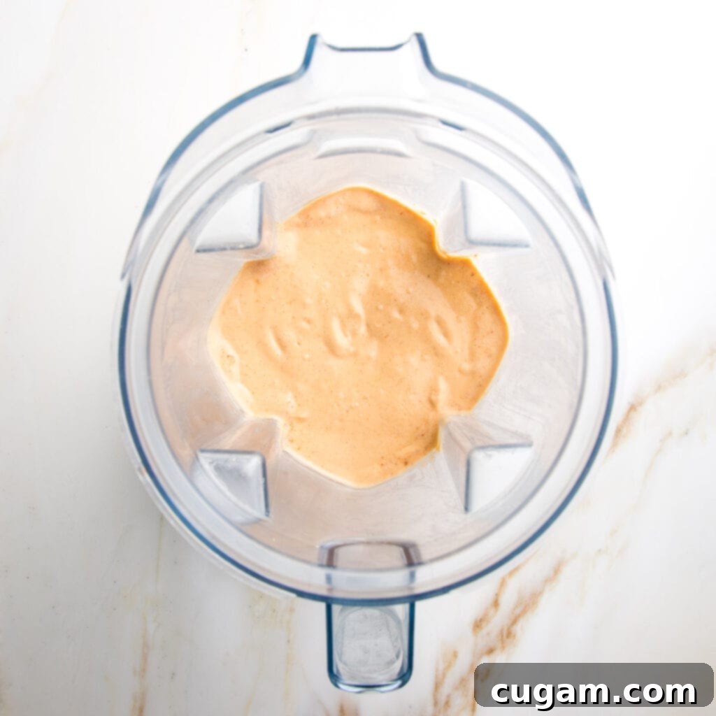Blender has finished blending, showing a smooth, creamy orange dressing.