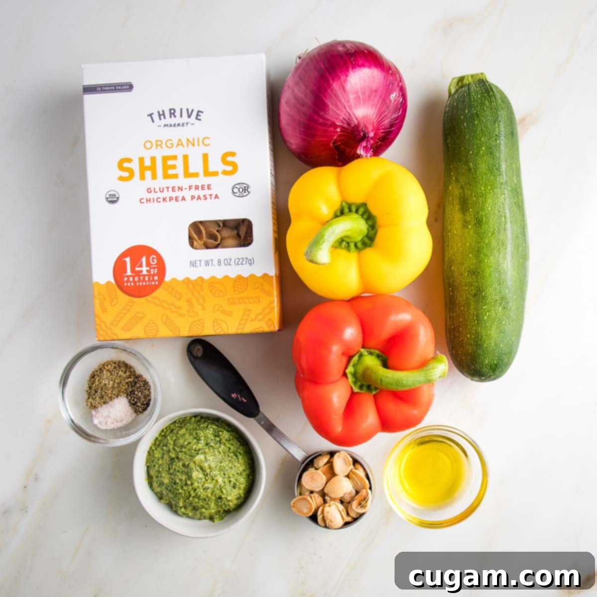 Ingredients for Pesto Pasta Salad: a box of gluten-free pasta, purple onion, yellow and red bell peppers, zucchini, olive oil, marcona almonds, pesto and spices. 