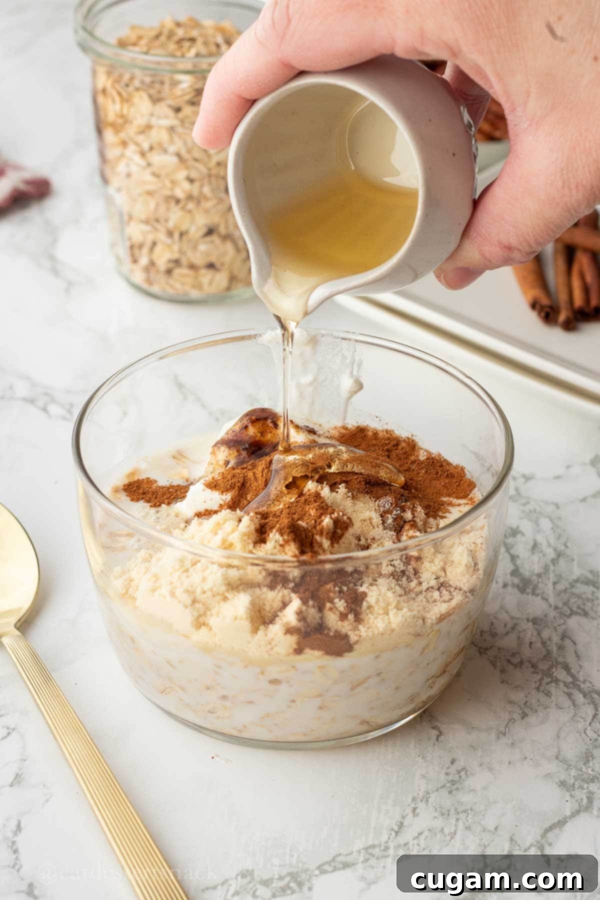 Pouring maple syrup into overnight oats bowl.