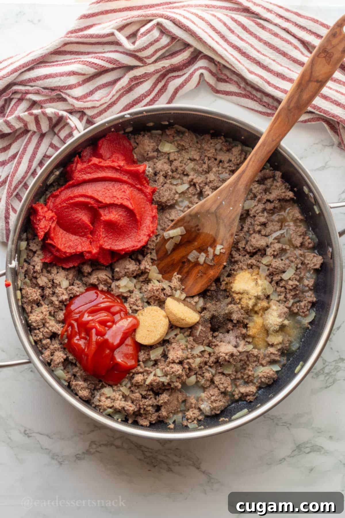 Tomato paste, ketchup, brown sugar, spices in ground turkey in metal pan.