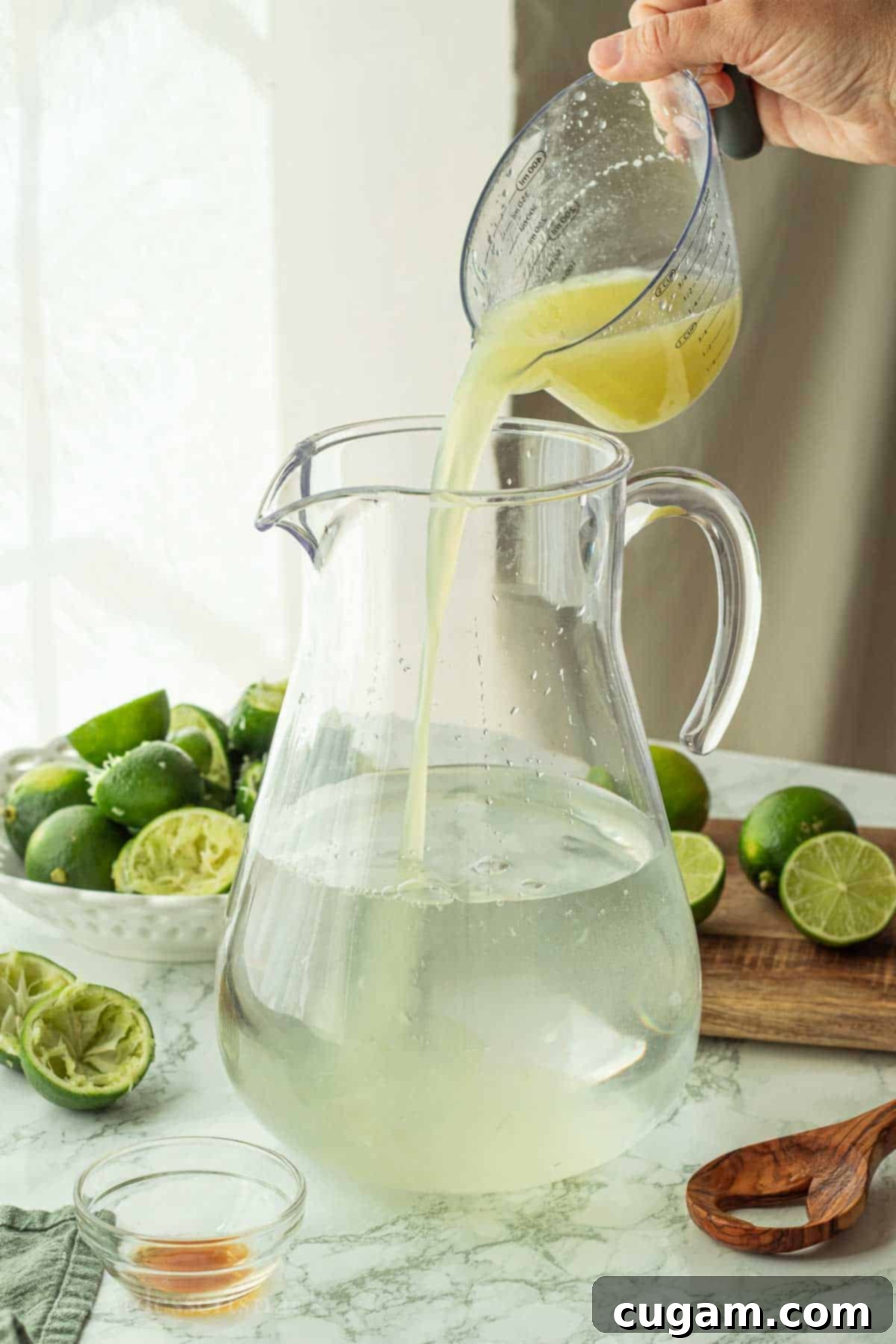 Adding freshly squeezed lime juice and vanilla extract into the pitcher with dissolved sugar and water.