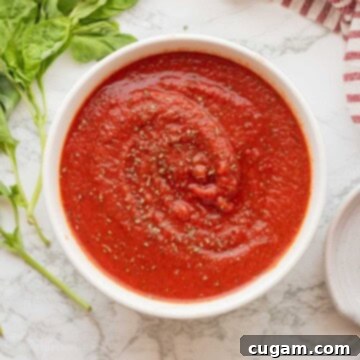 Thick homemade pizza sauce in a bowl with dried basil, ready for use.