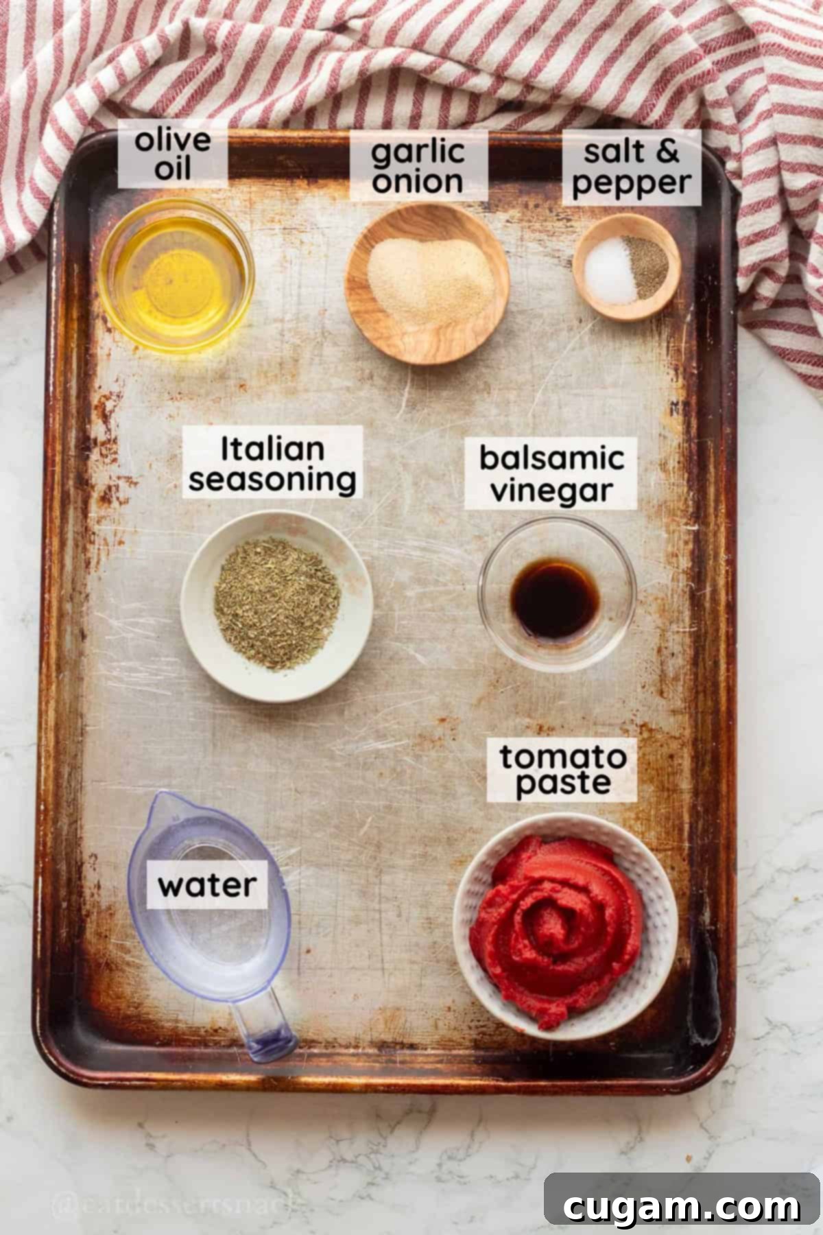 Labeled ingredients including tomato paste, olive oil, garlic powder, onion powder, salt, pepper, balsamic vinegar, Italian seasoning, and water on a metal pan for pizza sauce.