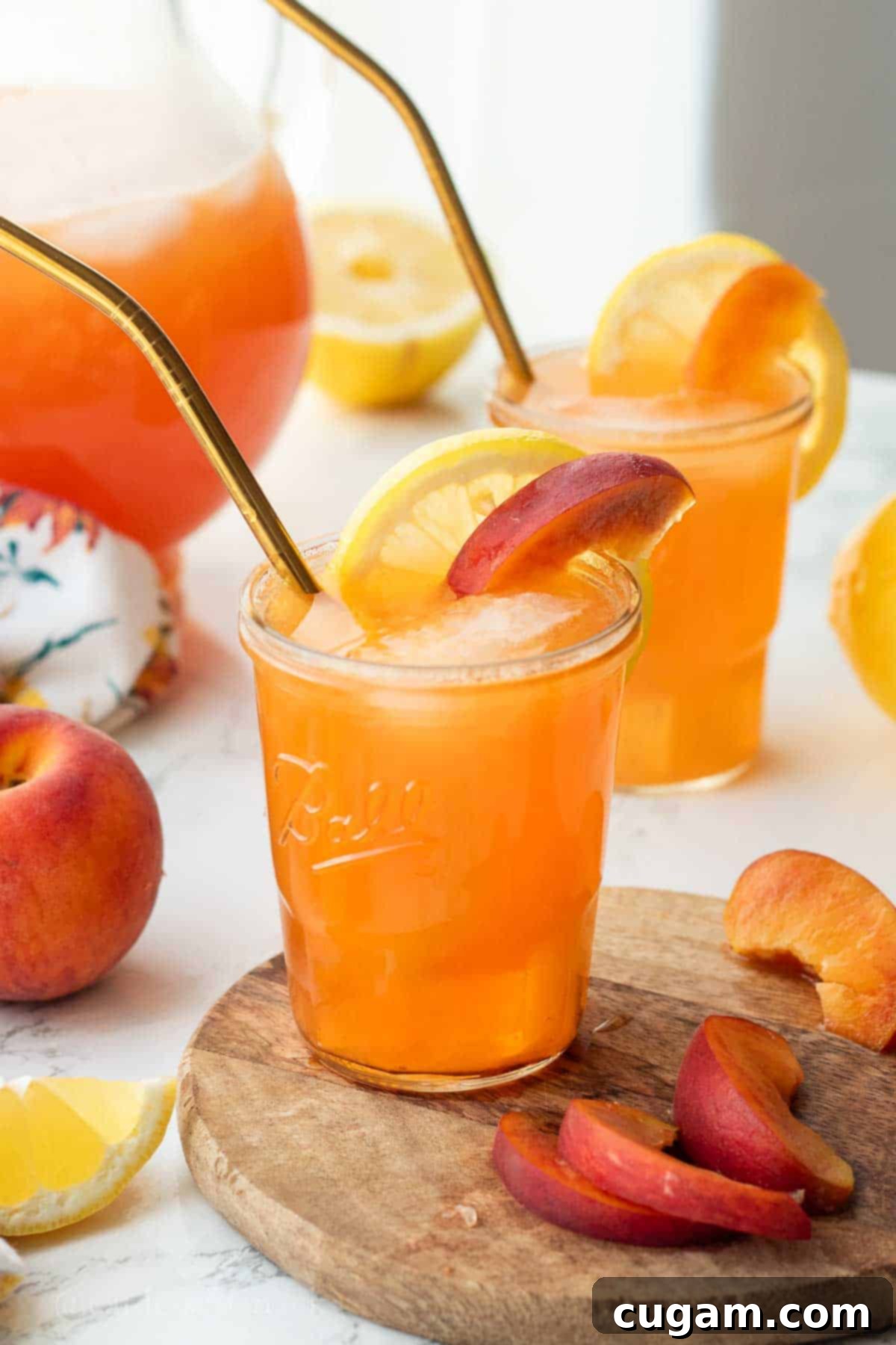 A refreshing glass of brown sugar peach lemonade, garnished with vibrant lemon and peach slices, and a straw, ready to be enjoyed.