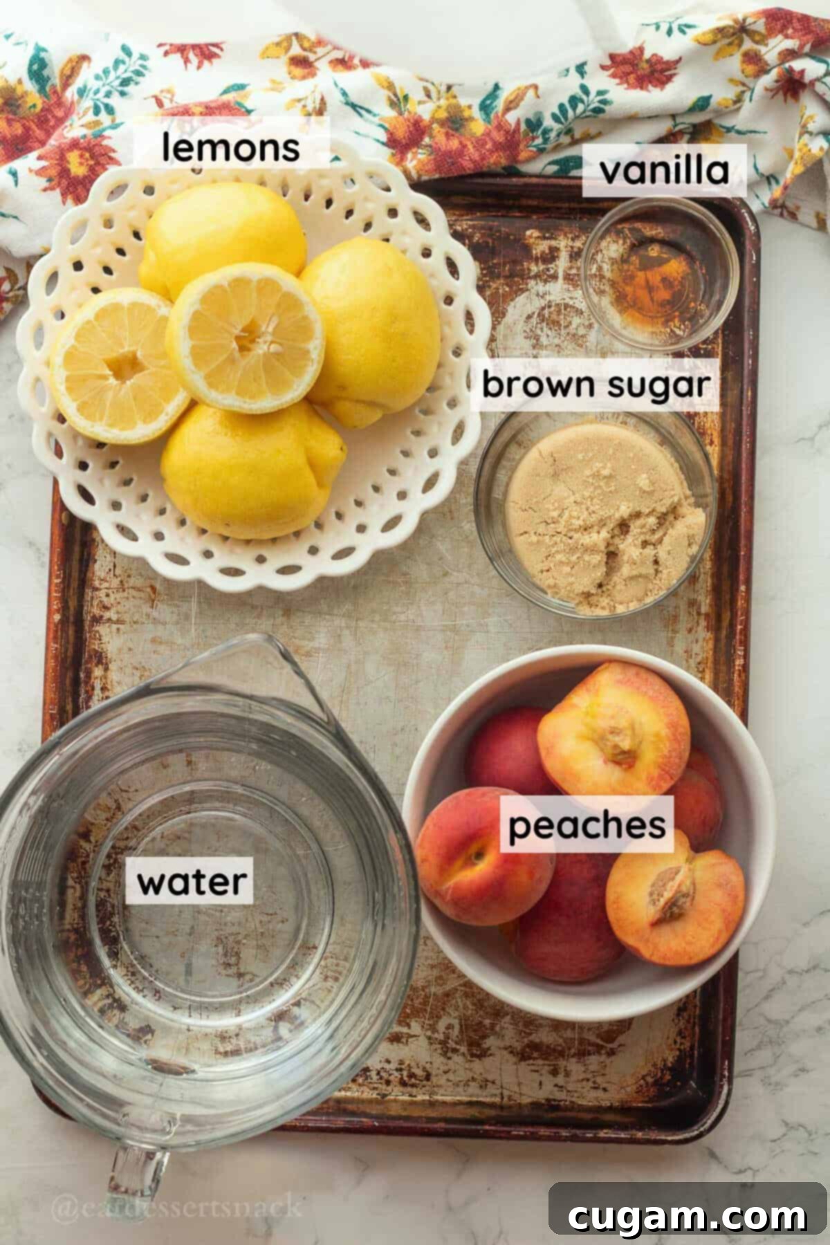 Clearly labeled ingredients for making peach lemonade, arranged neatly on a metallic baking sheet, showcasing freshness.