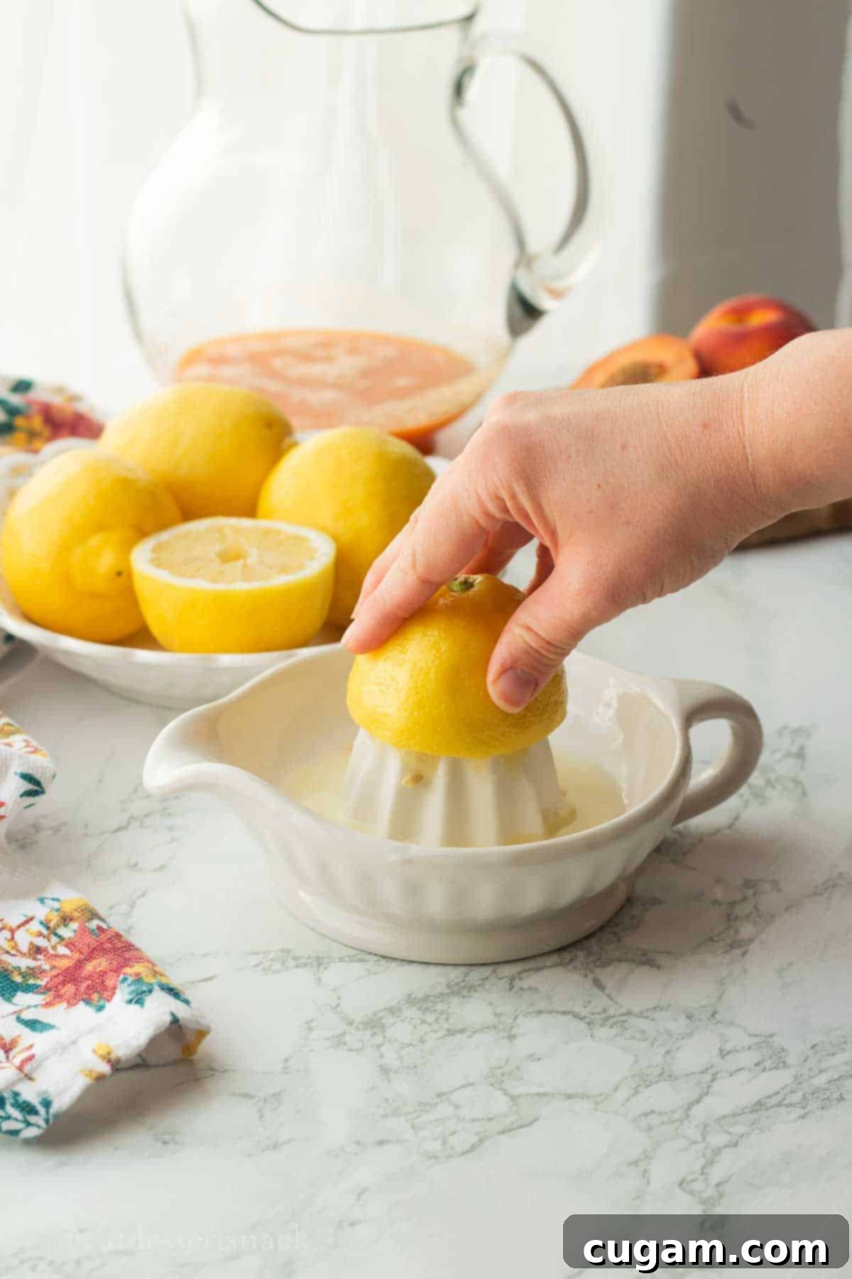 Hands squeezing fresh lemons directly into a glass dish, collecting the bright yellow juice.