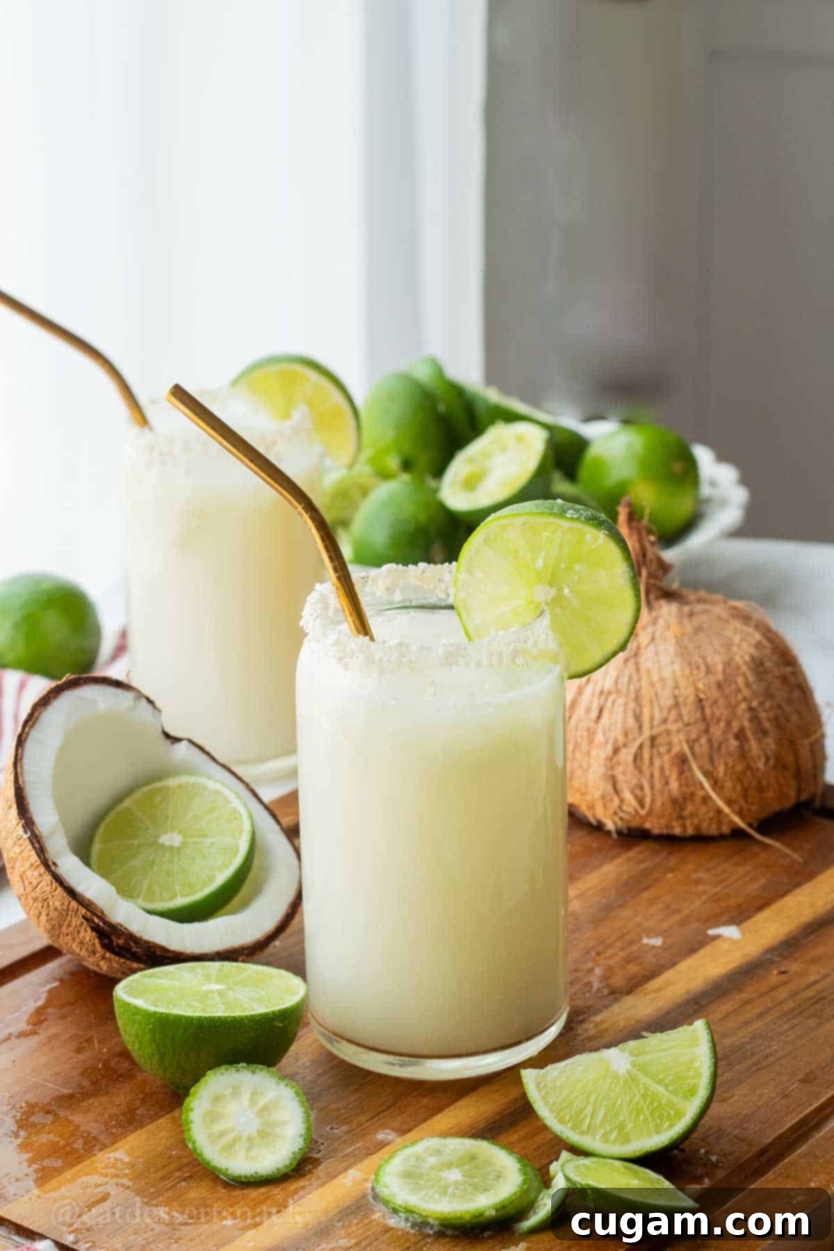 Glass of lime in the coconut drink with straw and lime slice and pitcher of limeade.