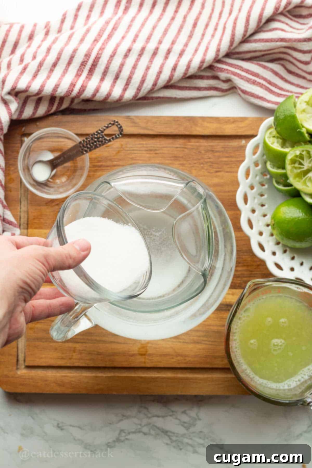 Pouring sugar into pitcher of water.