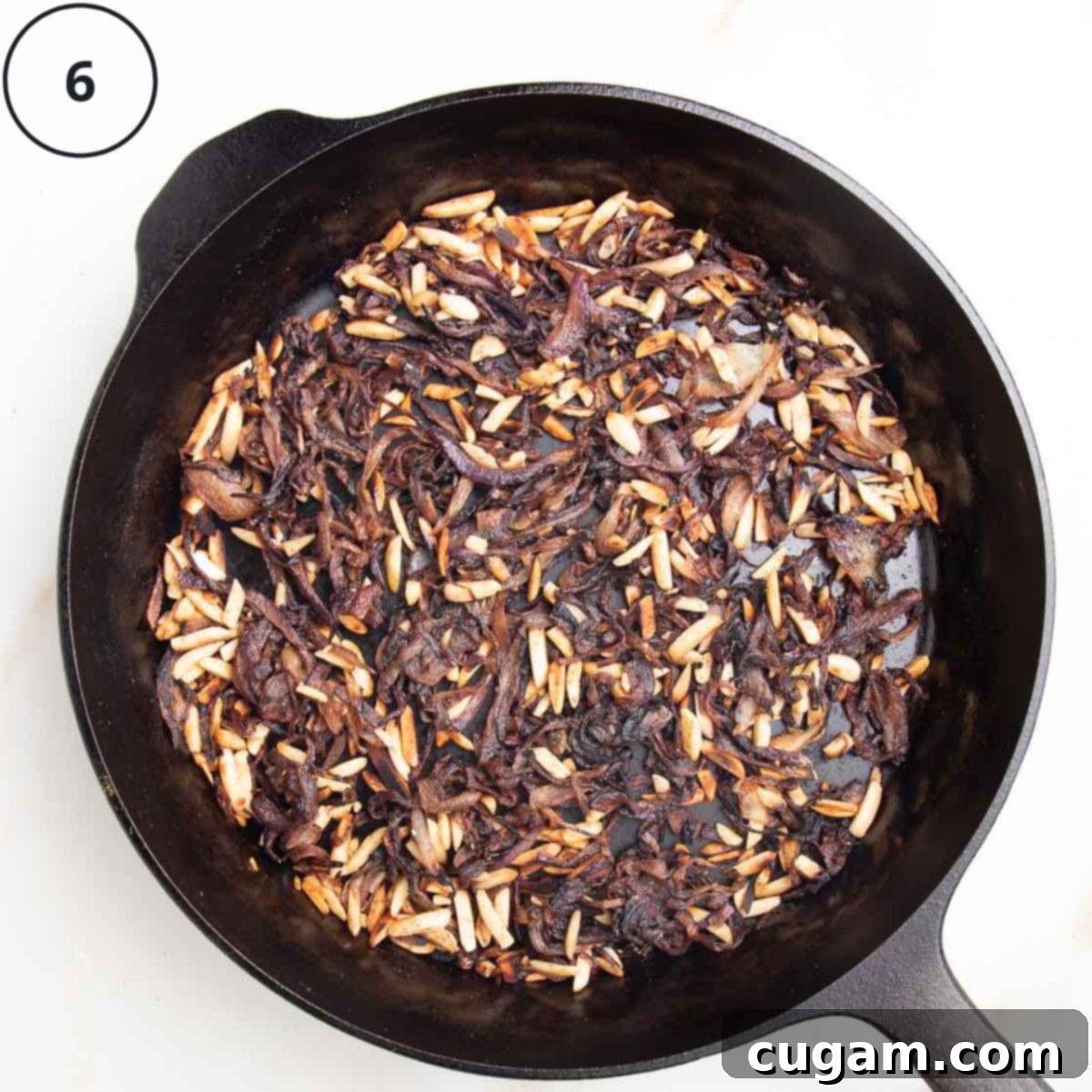 Caramelized onions, a fragrant mix of seasonings, and toasted nuts harmoniously combined in a cast iron skillet, labeled "6" to indicate the cooking stage.